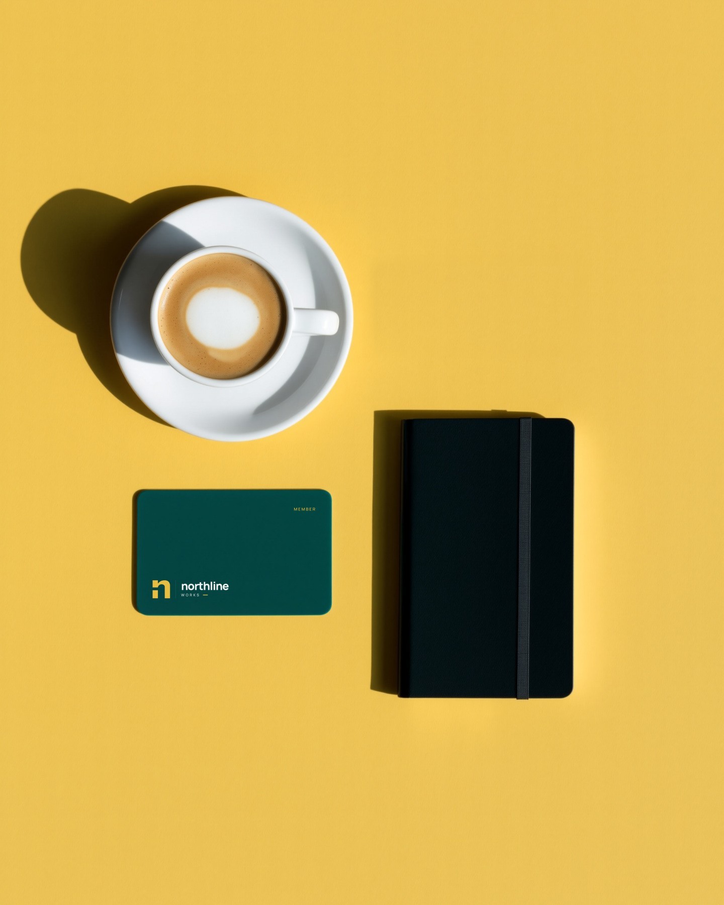 A Northline member card beside a coffee and a notebook on yellow